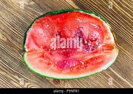 Schwarze und weiße Schimmel in einem saftigen roten Fruchtfleisch verrotten Wassermelone, Nahaufnahme, Ansicht von oben, Foto - Küche Holztisch Stockfoto