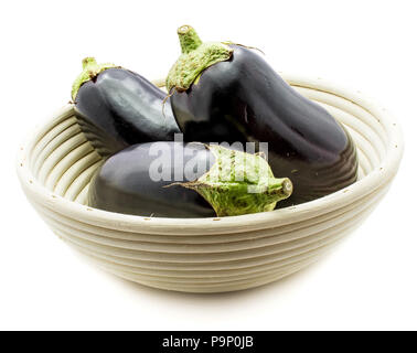 Ganze drei Eierfrüchte (Auberginen) in Rattan Schüssel auf weißem Hintergrund Stockfoto