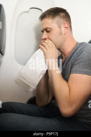 Reiseübelkeit. Mann fühlt sich sehr schlecht auf das Flugzeug. Stockfoto