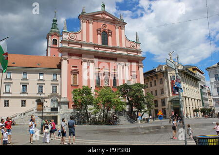 Ein glänzendes Tag in Ljubljana, die pinky Kirche Cerkev Marijenega steht im Mittelpunkt. Stockfoto