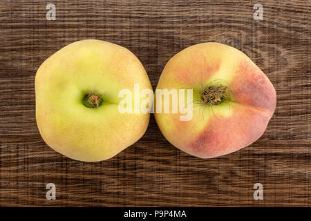 Zwei frische reife Saturn Pfirsiche flatlay auf braunem Holz Hintergrund Stockfoto