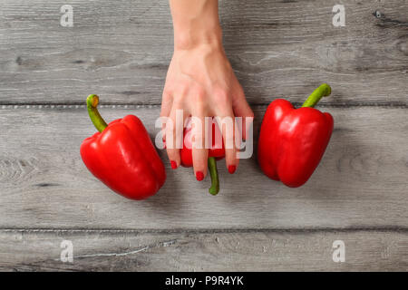 Table Top - grau Holz Schreibtisch und Frau Hände auf Red Paprika, zwei weitere auf jeder Seite. Stockfoto