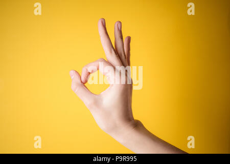 Frau Hand nach oben Okay, ja, die Annahme von Hand anmelden, um die Seite, Studio auf gelbem Hintergrund Stockfoto