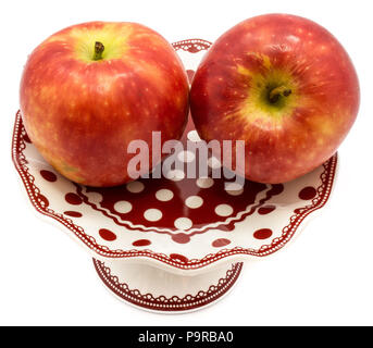 Zwei ganze rote Kanzi Äpfel auf Platte auf weißem Hintergrund Stockfoto