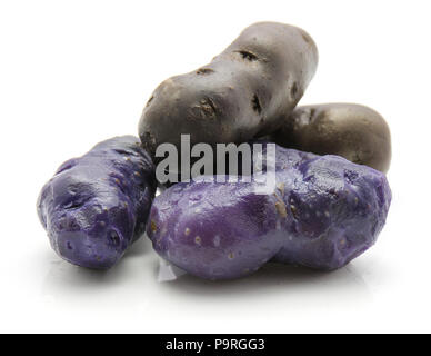 Vitelotte gekochte Kartoffeln isoliert auf weißem Hintergrund drei geschält und zwei ganze Lila Stockfoto