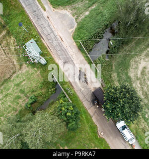 Vertikale Luftaufnahme der Überquerung eines Baches im Rahmen einer engen Straße mit einem Netzkabel, mit Drone Stockfoto