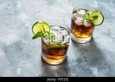 Rum und Cola Cuba Libre trinken mit Kalk und Eis auf rustikalen konkrete Tabelle Stockfoto