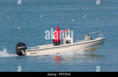Kleines Boot mit Außenbordmotor auf dem Wasser am Abend im Sommer in Großbritannien. Stockfoto