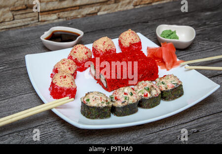 Japanische Küche. Bunte gebackenen Lachs Brötchen. Auf dem Tisch Sauce, Wasabi und Ingwer. Stockfoto