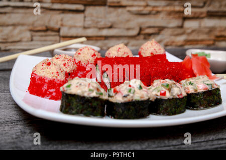 Japanische Küche. Nahaufnahme der Rollen und Sushi auf einem weißen Teller und Stäbchen. Stockfoto