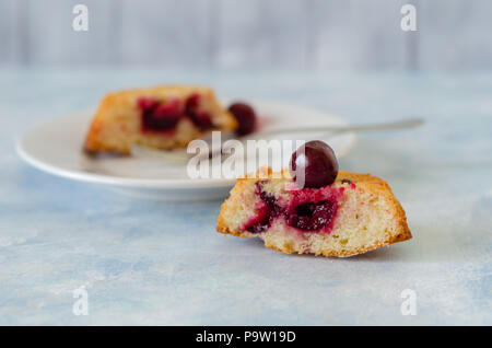Scheiben frischen iced Biskuitteig mit Kirschen auf rustikalen hölzernen Hintergrund Stockfoto