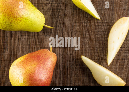 Gruppe von zwei ganze drei Scheiben frische rote Birne forelle Vielfalt flatlay auf braunem Holz Stockfoto