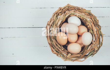 Eier von Hühnern in Weidenkorb auf weißem Holz- Hintergrund mit Kopie Raum Stockfoto