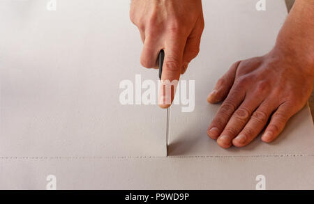 Man schneidet ein Blatt mit Wärmeschutzverglasung und Sound proof Material mit einem feststehenden Messer Stockfoto