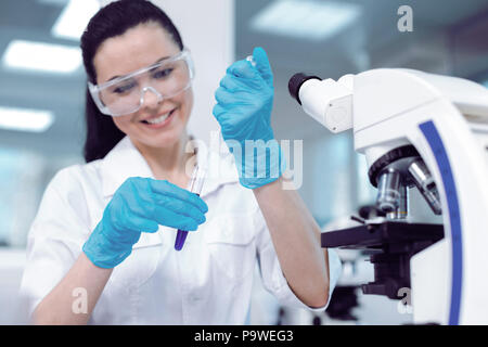 Für die Forschung. Freudige positive begeistert Wissenschaftler ein Reagenzglas und Entnahme einer Probe der Flüssigkeit, während eine Forschung Stockfoto