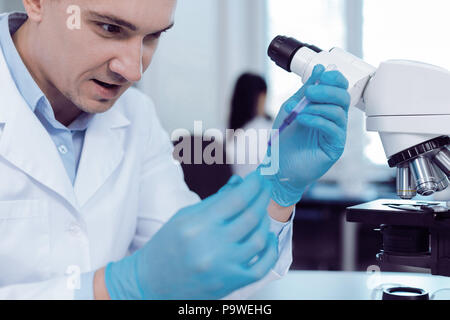 In der Forschung tätig. Smart angenehme begeisterte Wissenschaftler Gummihandschuhe zu tragen und dabei eine biologische Forschung beim Tragen Gummihandschuhe Stockfoto