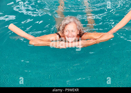 Lächelnde ältere Frau in den Swimming Pool tut, Aqua Fitness mit Schwimmweste Stockfoto