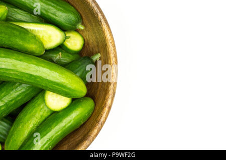 Fresh mini Gurken in eine hölzerne Schüssel flatlay auf weißem Hintergrund Stockfoto