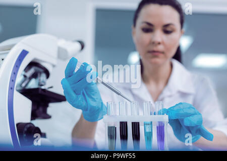 Medizinischen Test. Schwerwiegende attraktive intelligente Frau an der Reagenzgläser und unter Impfstoff Proben für die Analyse im Labor arbeiten suchen Stockfoto