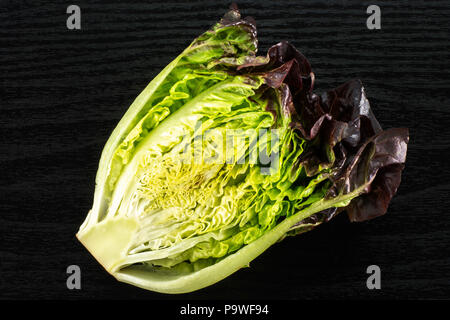 Die Hälfte der frischen grünen Salat rote kleine Juwel Vielzahl flatlay auf schwarzem Holz Stockfoto