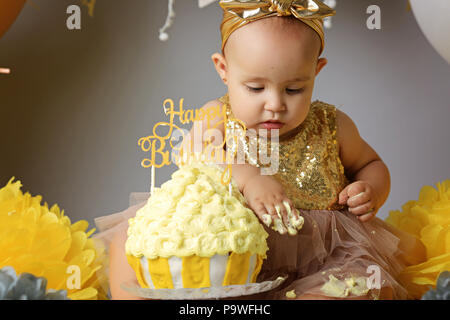 Lächelnden Mädchen ihren ersten Geburtstag feiern, Kuchen essen Stockfoto