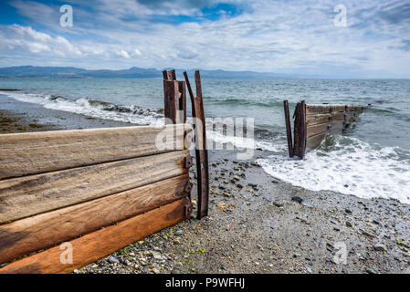 Sturm beschädigt Holz- buhnen und Rost Metall das Meer Küste in Criccieth Strand zu schützen, Wales, UK. Stockfoto