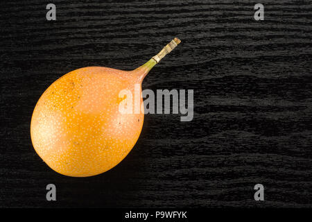 Riesige grenadill Tischplatte auf schwarz Holz Hintergrund eine süße Frische gelbe Leidenschaft Obst isoliert Stockfoto