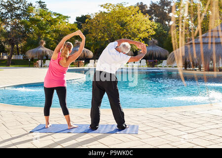 Senior Paar am Pool tun, eine Dehnung Übung auf einer Spa Ferienhäuser Stockfoto