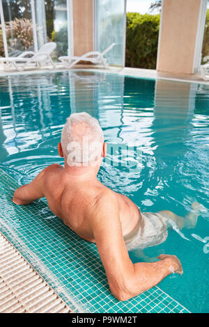 Alter Mann entspannt am Pool im Hotel Spa Stockfoto