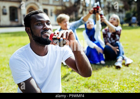 Fröhlicher Kerl Lächeln beim Trinken von Soda im Freien Stockfoto