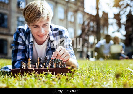 Lächelnd Kerl Spiel Schach im Freien genießen. Stockfoto