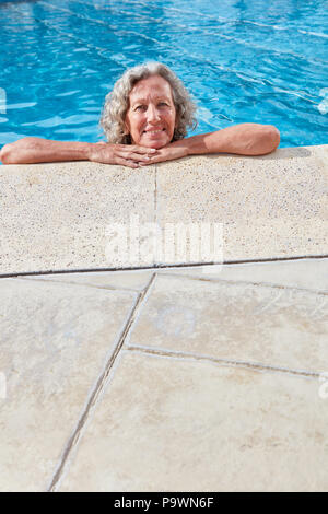 Lächelnd senior Frau entspannend am Pool im Freibad im Sommer Stockfoto