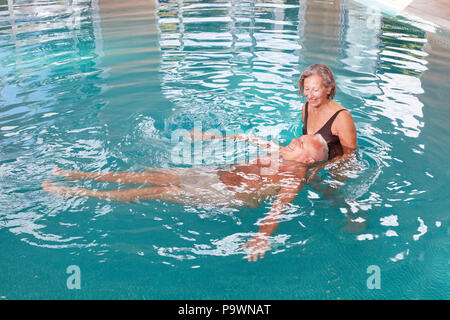 Älterer Mann erhält Hydrotherapie im Pool, der von einem Physiotherapeuten Stockfoto