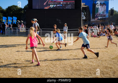 Mädchen und Jungen schlagen bis eine spontane Spiel der Fußball in den wichtigsten Obelisk Arena während einer Band spielen auf der anderen Seite des soundstack. Samstag nach Stockfoto