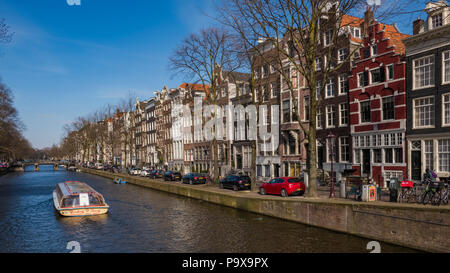 Amsterdam. Hohe schmale Kanalhäuser und ein Touristen-Kreuzfahrtschiff auf einem Kanal in Amsterdam, Niederlande, Europa Stockfoto