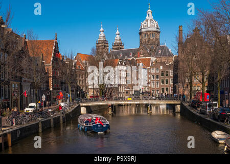 Viele Fahrräder auf einer Brücke mit Blick auf eine Gracht in Amsterdam, Niederlande, Europa mit einem Boot unter Segeln Stockfoto