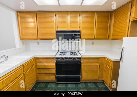 Alte Wohnung Küche mit Eiche Schränke, Arbeitsplatten Fliesen, Gasherd und grünem Vinyl Bodenbelag. Seit 1988 unverändert. Stockfoto