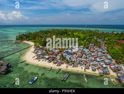 Drone Foto von einem sehr schlechten Bajau Sea Gypsy Village auf Mabul Island, Sabah, Malaysia (Borneo), mit tropischen Meer, blauer Himmel & Wolken im Hintergrund. Stockfoto