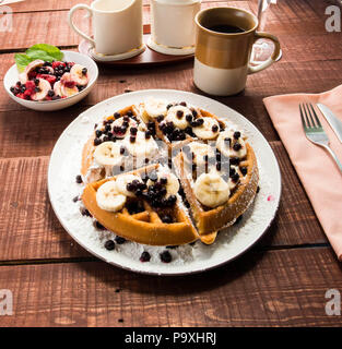 Waffel mit Bananen, Blaubeeren und Kaffee auf einem Tisch Stockfoto