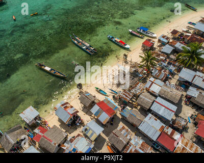 Eine Drohne Foto auf einem sehr schlechten Bajau Sea Gypsy Village, und Strand, Boote, und flachen tropischen Wasser, auf Mabul Island, Sabah, Malaysia. Stockfoto