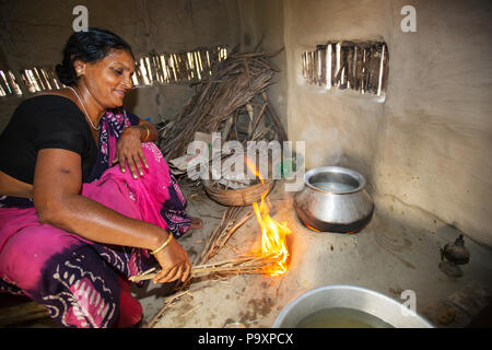 Eine Dorfbewohner in einem abgelegenen Dorf auf einer Insel in den Sundarbans, dem Ganges-Delta im Osten Indiens, das sehr anfällig für den Anstieg des Meeresspiegels ist. Sie kocht auf einem traditionellen Lehmofen, der mit Biokraftstoff (Reisstiele) und kohlenstoffarmem Kochen betrieben wird. Stockfoto
