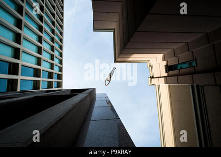 Ansicht von unten der männlichen parkour Sportler von einem Dach zum anderen springen Stockfoto