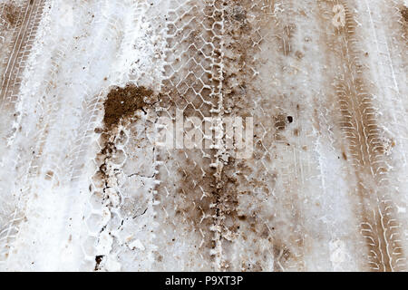 Spuren von PKW-Reifen auf Schnee mit Sand für besseren Halt der Autos und der Weg bedeckt, Foto im Winter und close-up Stockfoto