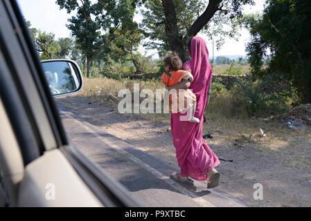 Indische lokale Frau mit Kind, Wandern am Straßenrand in Indien Stockfoto