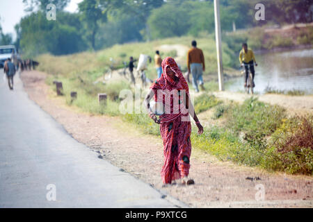 Indische lokale Frauen Ehefrauen der Landwirte, zu Fuß nach Hause nach dem Handel am lokalen Markt ausgeht, die ihre Produkte auf ihren Köpfen. Stockfoto