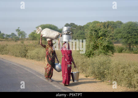 Indische lokale Frauen Ehefrauen der Landwirte, zu Fuß nach Hause nach dem Handel am lokalen Markt ausgeht, die ihre Produkte auf ihren Köpfen. Stockfoto