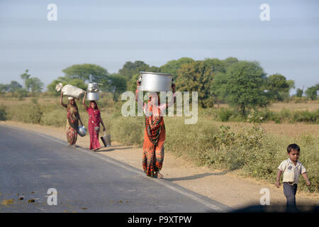 Indische lokale Frauen Ehefrauen der Landwirte, zu Fuß nach Hause nach dem Handel am lokalen Markt ausgeht, die ihre Produkte auf ihren Köpfen. Stockfoto