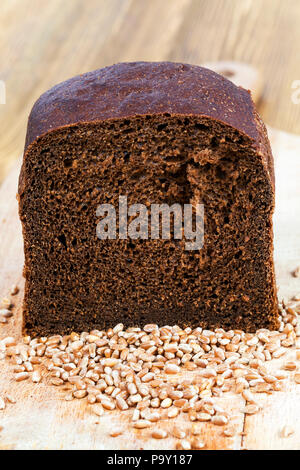 Eine halbe schwarz Laib Schwarzbrot auf eine dünne weiße pita Brot mit verstreut liegenden Körner von Getreide Stockfoto