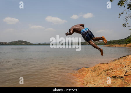 Eine junge muskulöse athletischen Mann nimmt einen Salto Eintauchen in den Fluss in den Morgen. Stockfoto