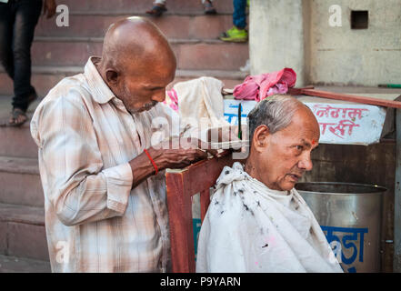 Indische Friseur außerhalb schneiden Haare an den ghats von der Ganges in Indien Varenasi Stockfoto